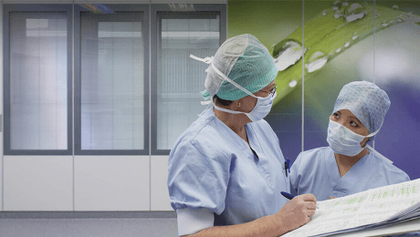 Medizinisches Personal vor einer Wand aus bedrucktem Reinraumglas und 3 Reinraum-Fenstern mit Sichtschutz.