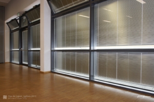 Große Fenster mit sturmfesten Raffstores im Scheibenzwischenraum. Auch die Tür und die gekippten Oberlichter haben eigene Jalousien, die sich mit öffnen.