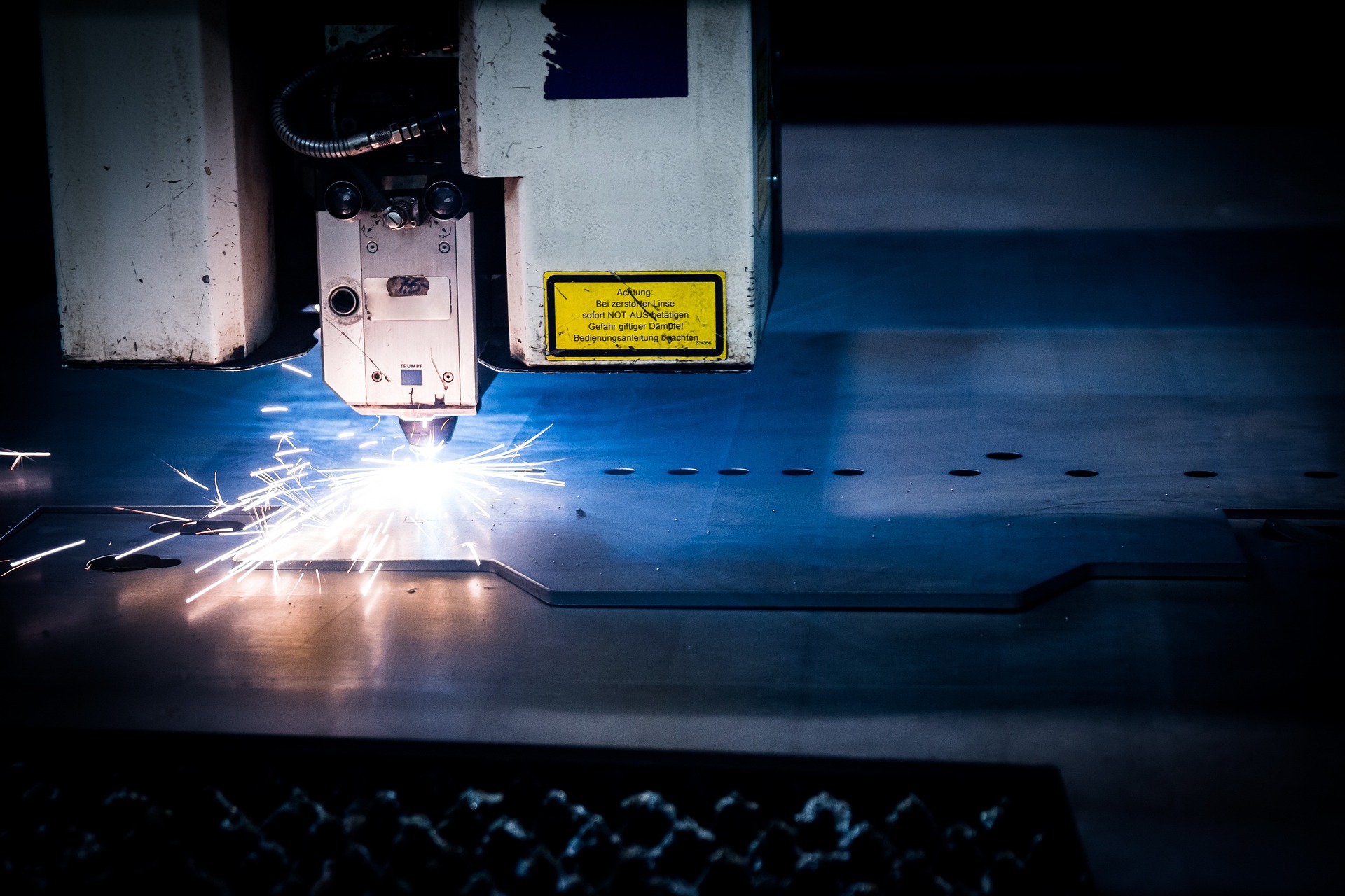 Ein Laserschneider bearbeitet dickes Stahlblech in einer Laserkabine. Ein Laserschneider bearbeitet dickes Stahlblech in einer Laserkabine.